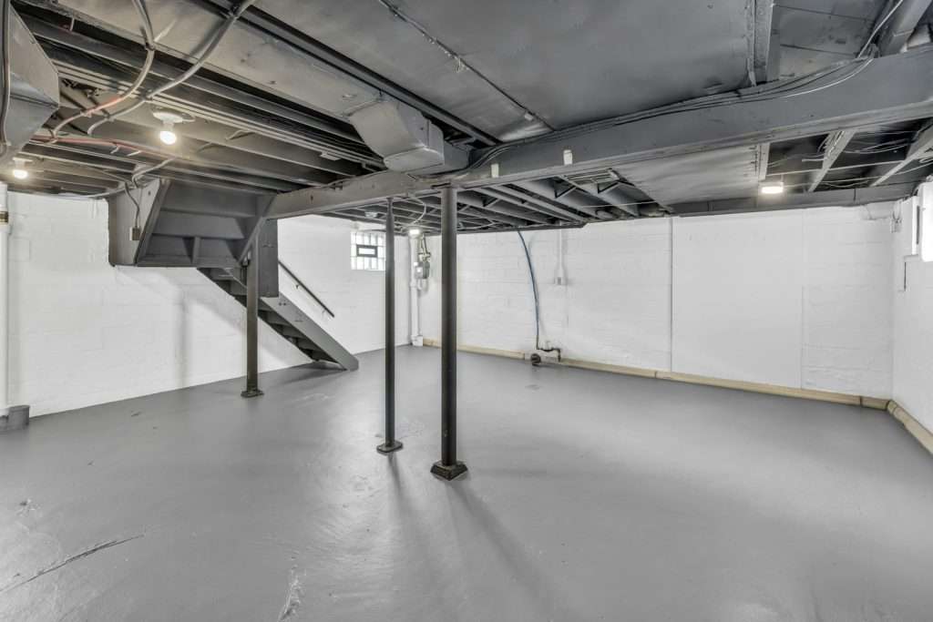 Unfinished basement with exposed joists and support posts