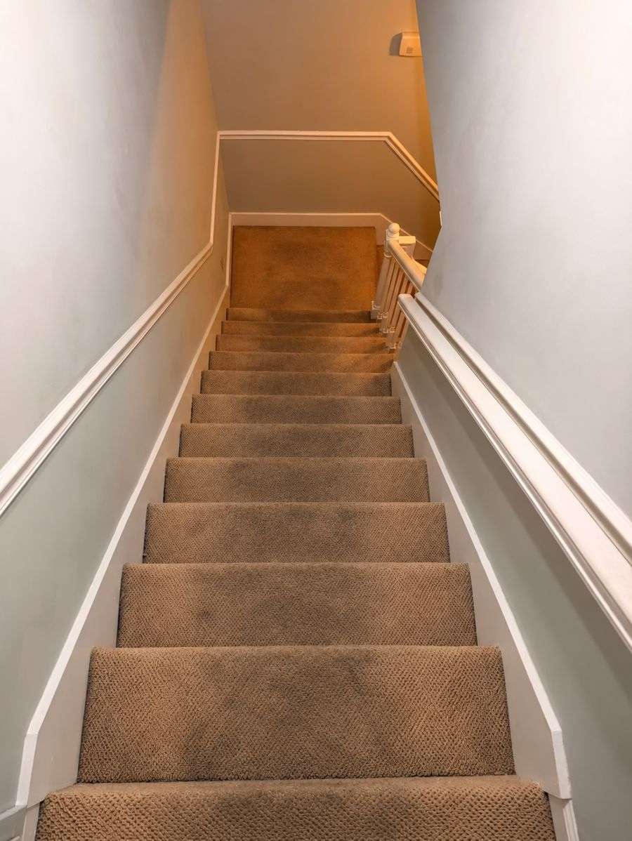 Carpeted staircase with dark traffic wear on the steps in a Tullahoma home before cleaning