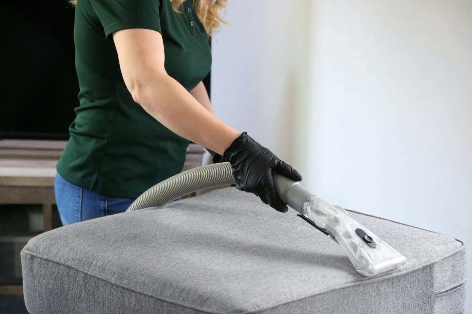 Technician cleaning a gray sofa cushion with an upholstery extraction tool